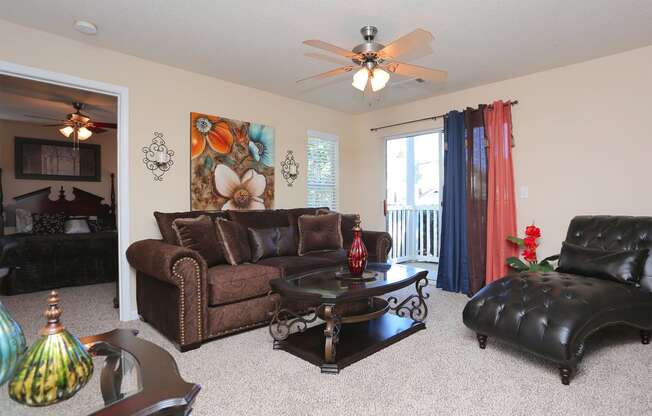 a living room with leather furniture and a ceiling fan