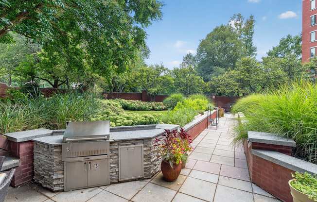 A patio with a grill and potted plants.
