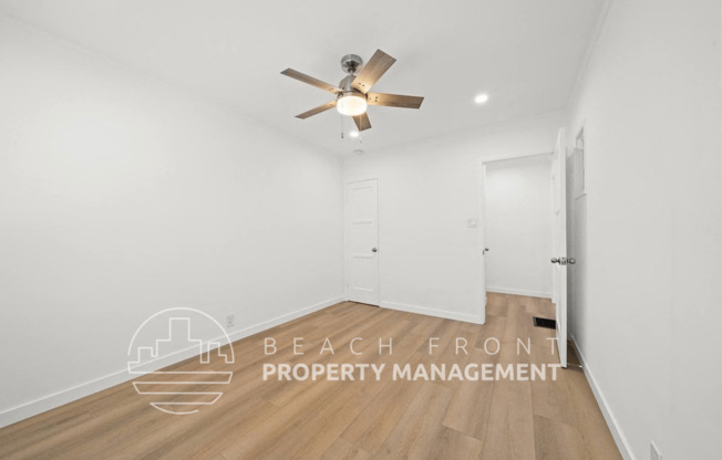 a room with white walls and a ceiling fan and a door