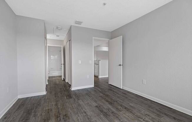 the living room of an apartment with white walls and wood flooring