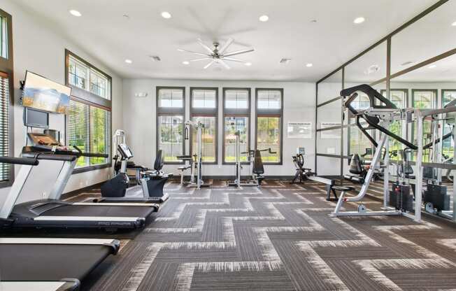 a gym with treadmills and other exercise equipment and windows