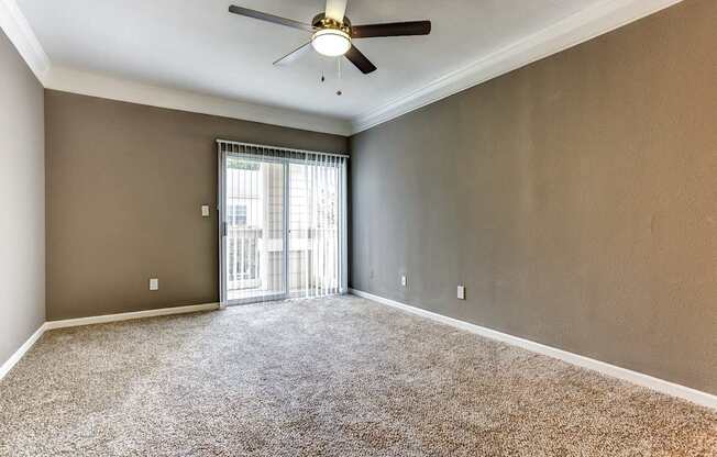 Upgraded living area with crown molding, carpet, and sliding glass door that leads to balcony