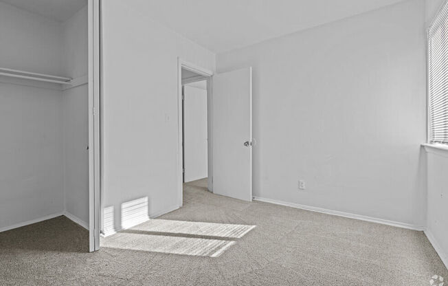 the living room of an apartment with white walls and carpet