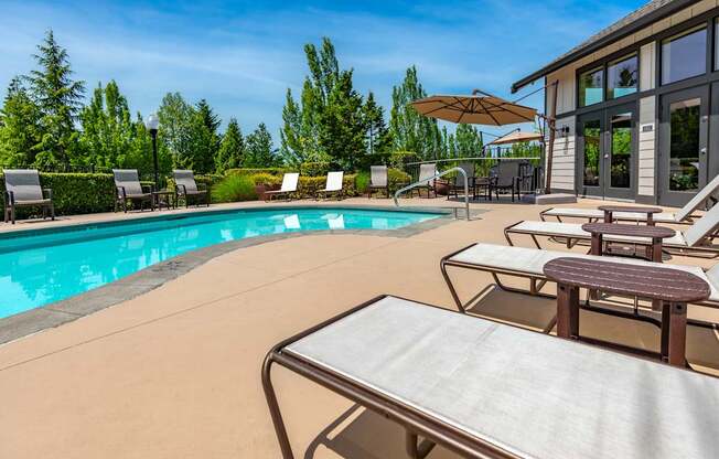 A poolside table is in front of a pool with chairs around it.