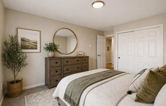 A bedroom with a large bed and a round mirror on the wall.