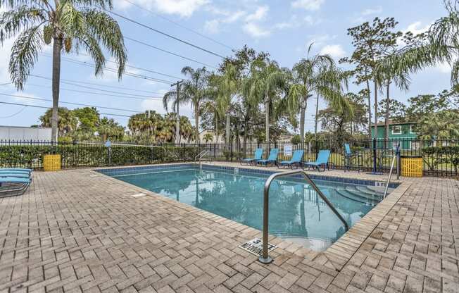 a swimming pool with blue chairs and palm trees