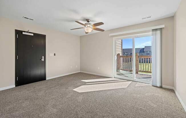 Living room with ceiling fan and front black door at Olde English Village