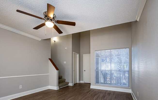 A room with a ceiling fan and a staircase.