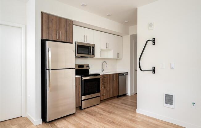 a kitchen with stainless steel appliances and a wood floor in an apartment