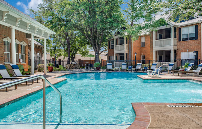A swimming pool in front of a building with a white pergola.