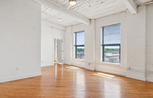 A large empty room with wooden floors and white walls.