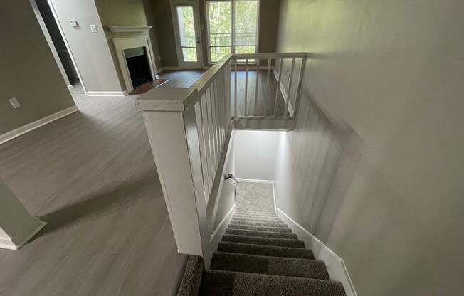 A staircase with a carpeted runner and white railings leads to a second floor.
