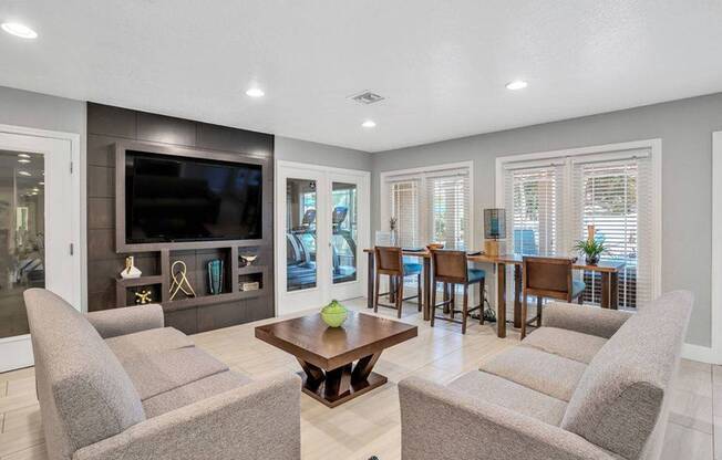 Canopy leasing center lounge area with two gray couches, bar area, and big screen television