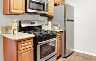 A kitchen with a stove, refrigerator, and microwave.