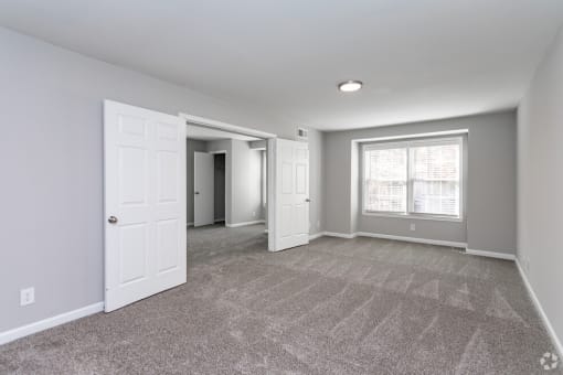 an empty room with white doors and a window