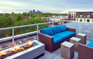 A patio with a blue couch and a fire pit.