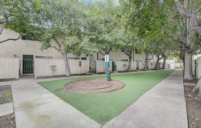 a courtyard with green grass and trees in front of a building