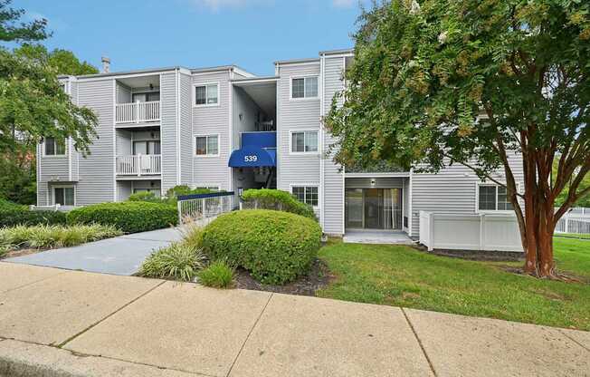 an apartment building with white siding and a sidewalk at ReNew Odenton