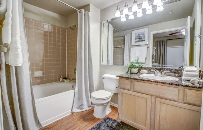 Master bathroom with soaking tub, tile backsplash, large mirror and wood style flooring