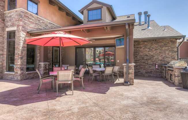 a patio with a grill and tables with umbrellas