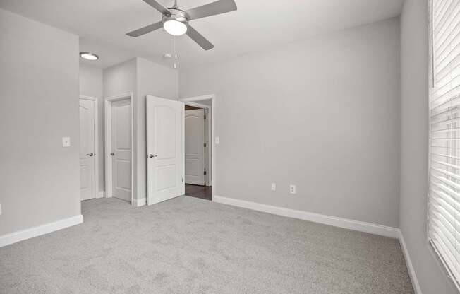 A room with a ceiling fan and carpeted floor.