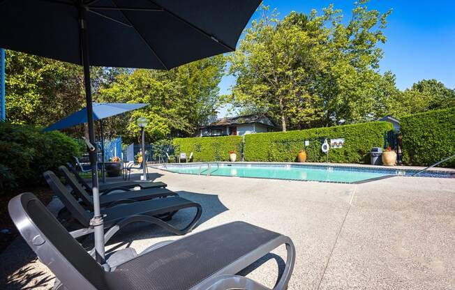 a pool with lounge chairs and umbrellas Copper Ridge Apartments, Renton, 98055