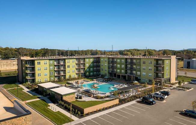 A large apartment complex with a pool in the middle of the parking lot.