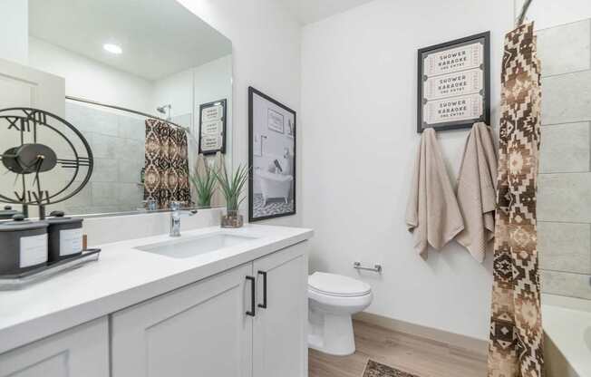 A bathroom with a white toilet, sink, and a framed picture on the wall.