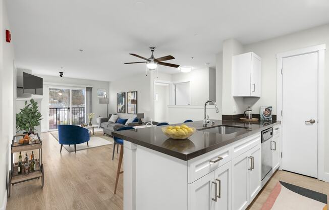 a kitchen and living room with white walls and wood flooring