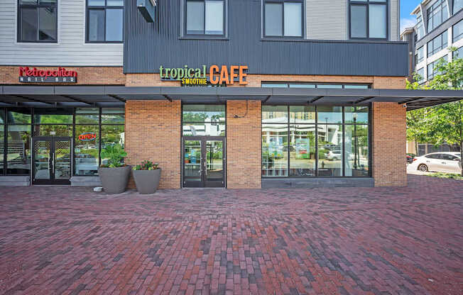 A brick walkway leads to a cafe with a red awning.