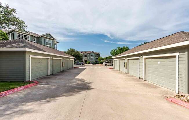 A row of garages with a driveway in between them.
