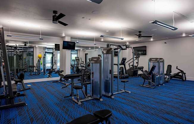 A gym with a variety of equipment including treadmills, weights, and exercise machines.