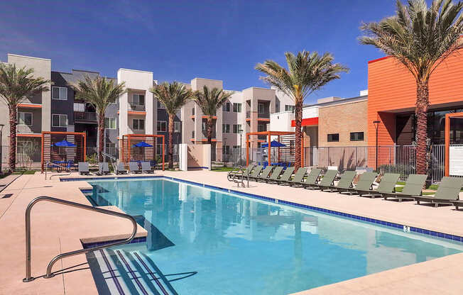 A swimming pool in front of a building with palm trees.
