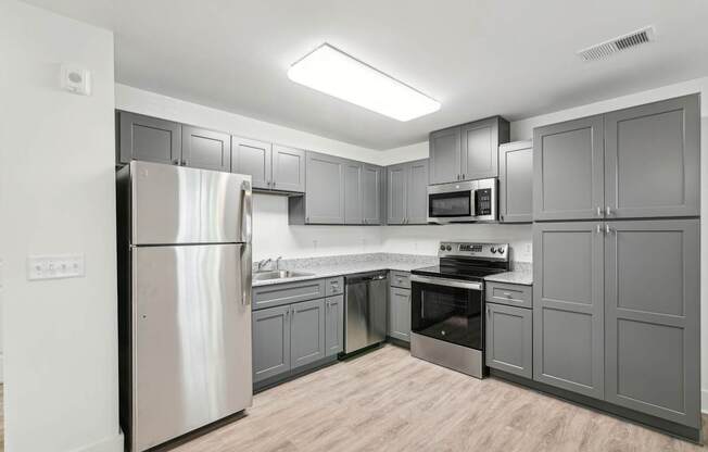 A kitchen with a refrigerator, oven, and microwave.