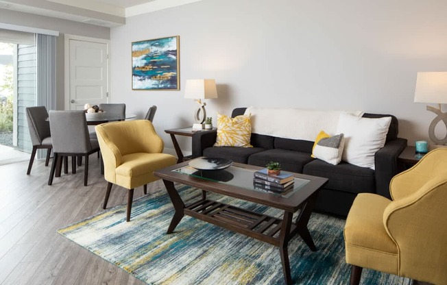 A living room with a grey couch, a yellow chair, and a coffee table.