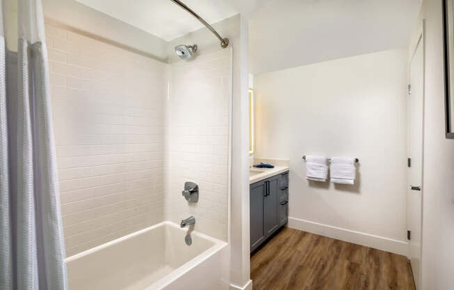 A white bathroom with a white tub and a white shower head.