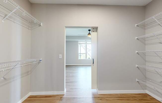 a walk in closet in a home with white walls and a door to a room