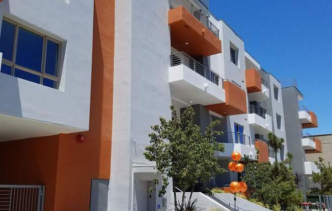 A modern apartment building with orange and white balconies at Woodley Sara Apartment, Van Nuys