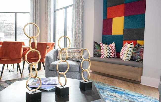A living room with a grey couch, a red chair, and a coffee table with three golden rings on it.