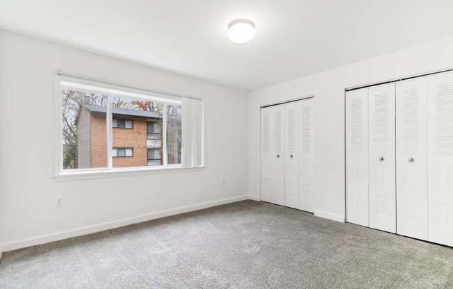 a room with two closets and a window and a carpeted floor