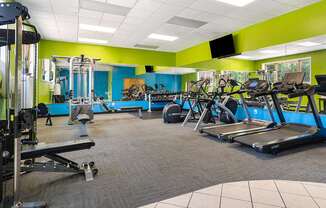 A gym with a variety of equipment including treadmills, weights, and exercise machines.