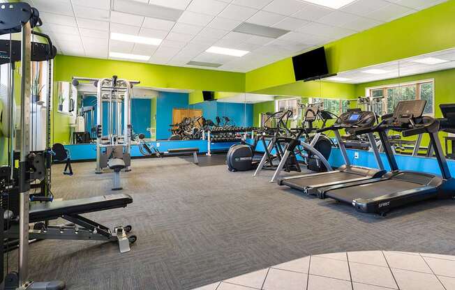 A gym with a variety of equipment including treadmills, weights, and exercise machines.