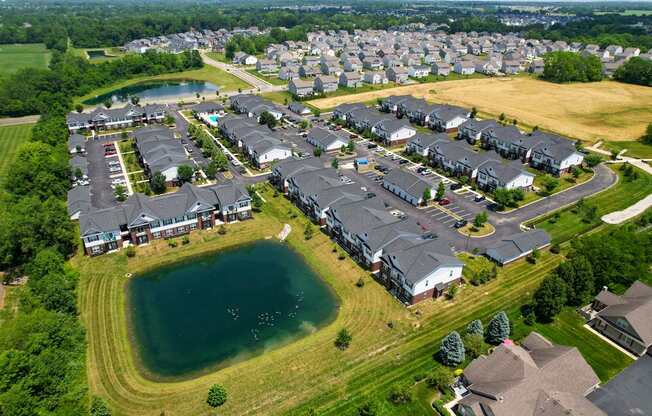A bird's eye view of a residential area with houses surrounding a lake.
