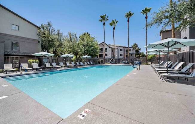 A large swimming pool surrounded by lounge chairs and umbrellas at Lazo Apartment Homes, Chandler .