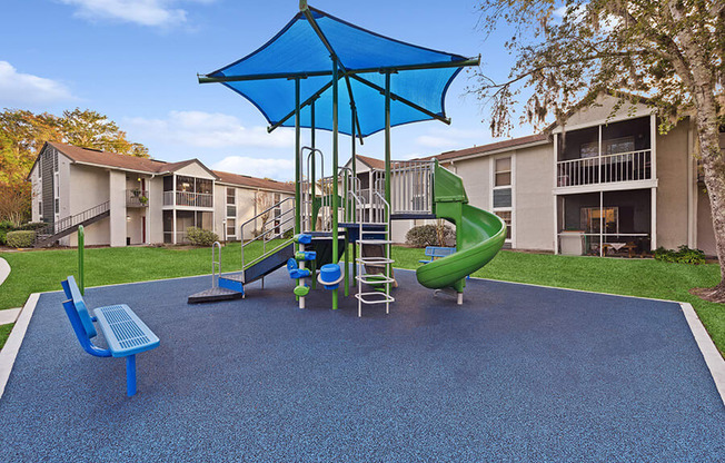 Community Playground with Slide and Blue Canopy at Vue at Baymeadows Apartments in Jacksonville, FL.