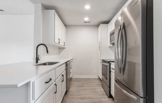 an empty kitchen with white cabinets and stainless steel appliances
