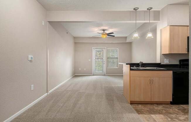 A spacious dining and living room with a fan on the ceiling and a carpeted floor at Lynbrook Apartments and Townhomes, Elkhorn, NE, 68022