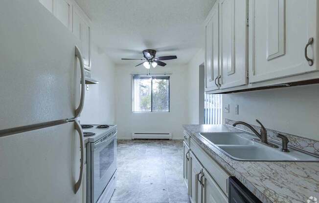 A kitchen with a white refrigerator, a window, and a ceiling fan.