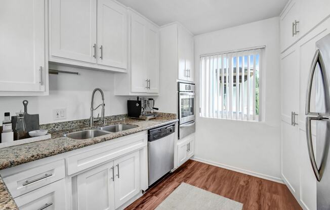 a kitchen with white cabinets and black counter tops and a window