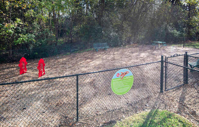 A fenced area with a sign and red objects in the distance.